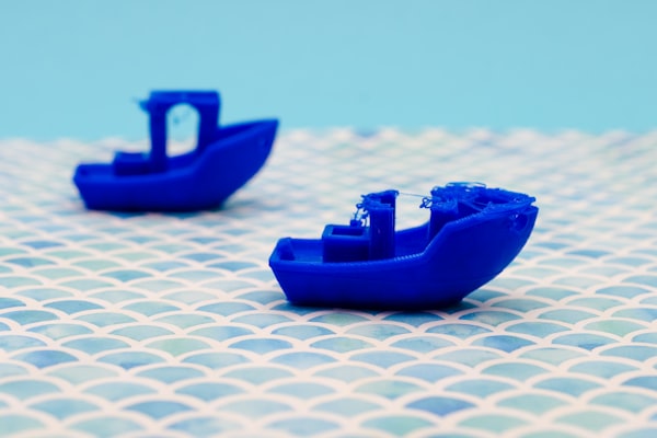 Picture of a failed 3D printed blue boat, and another one in second plane