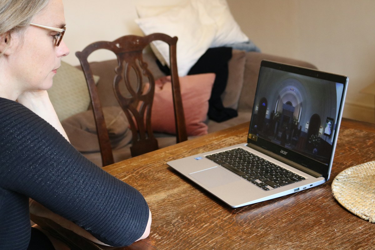 A woman sits at a table with a laptop, organizing a parent-teacher conference schedule.