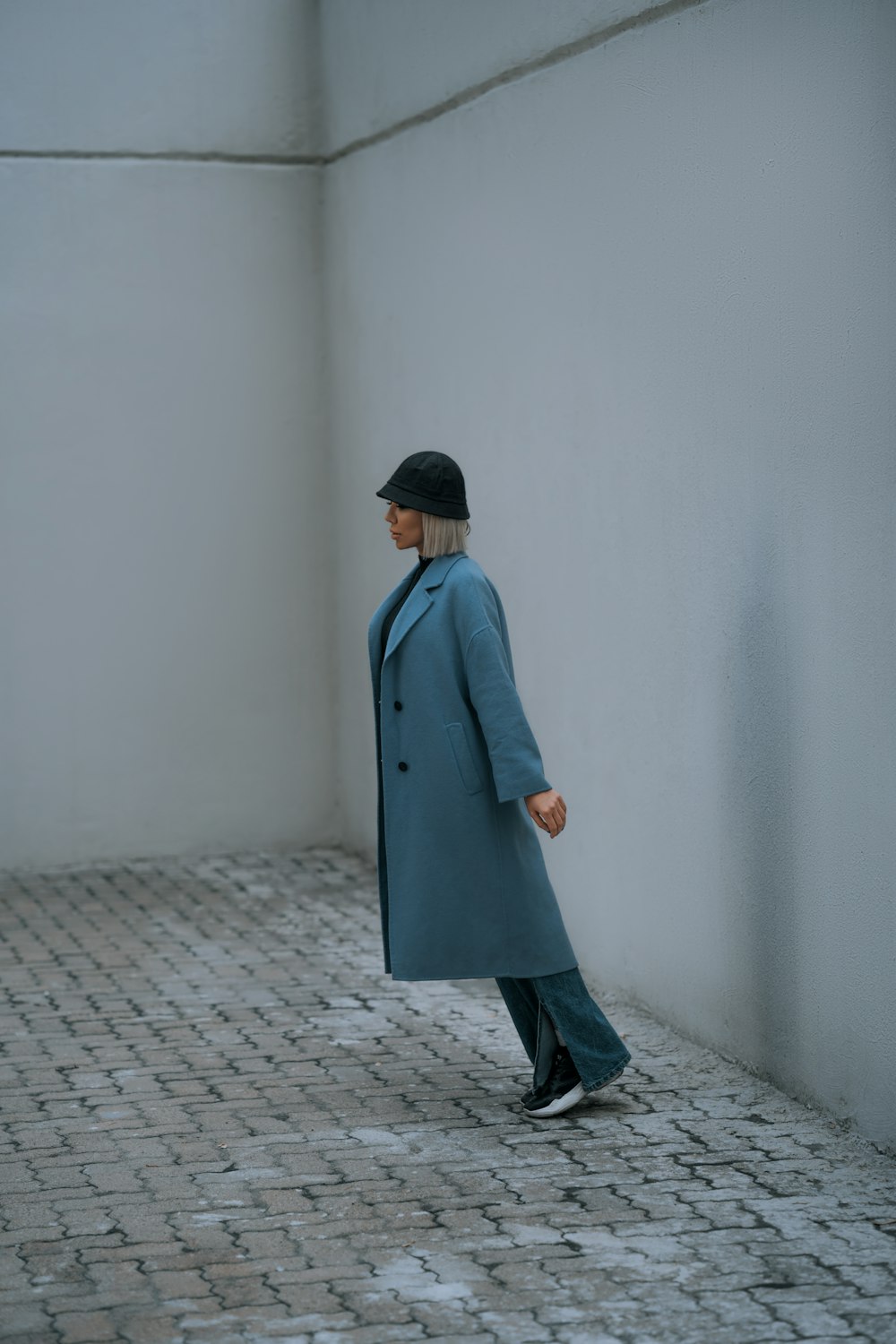 a woman in a blue coat and hat walking