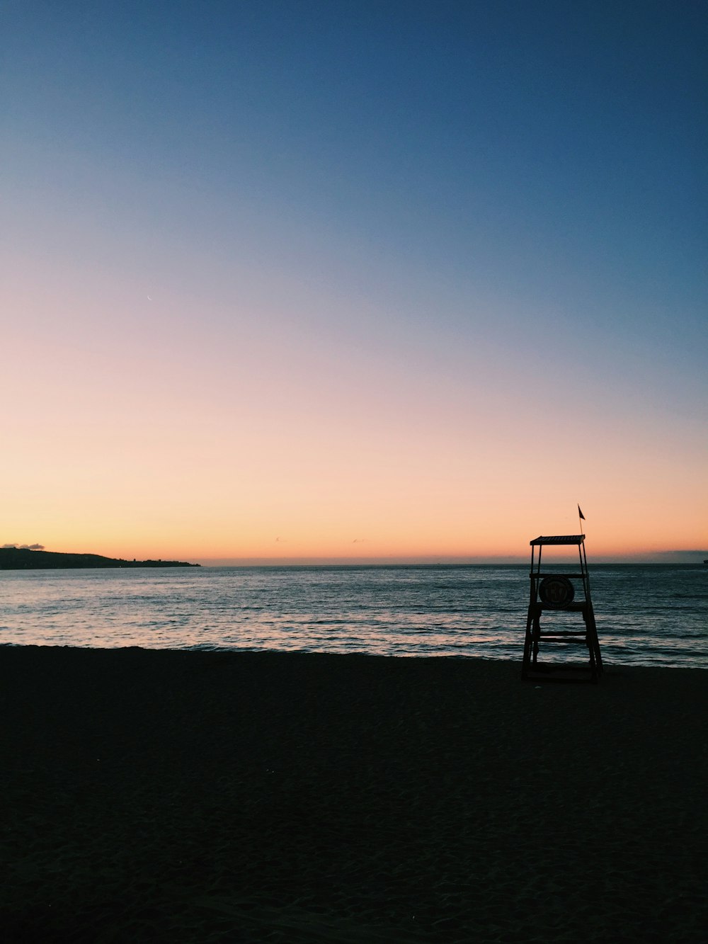 a lifeguard chair on a beach at sunset