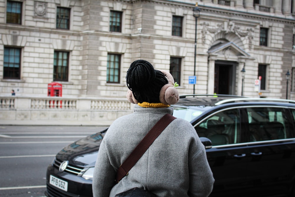 a woman walking down a street past a car