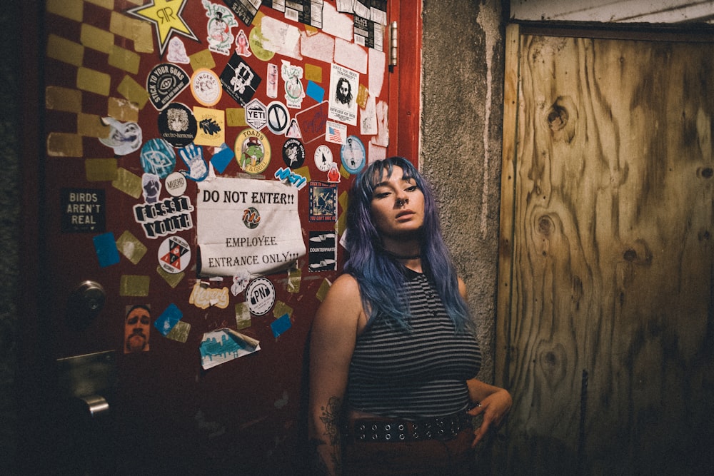 a woman with blue hair standing in front of a door