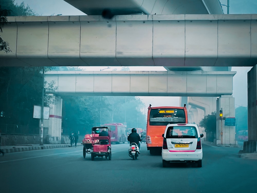 a group of vehicles driving down a street under a bridge