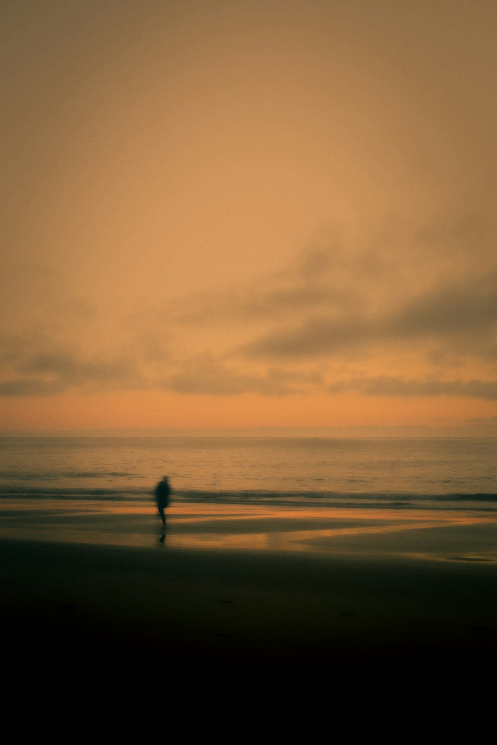 Una persona caminando en una playa al atardecer