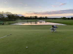 Players lining up their putts on a sunny day with spectators watching