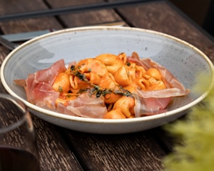 a bowl of pasta with ham and cheese