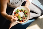 a woman is holding a bowl of food