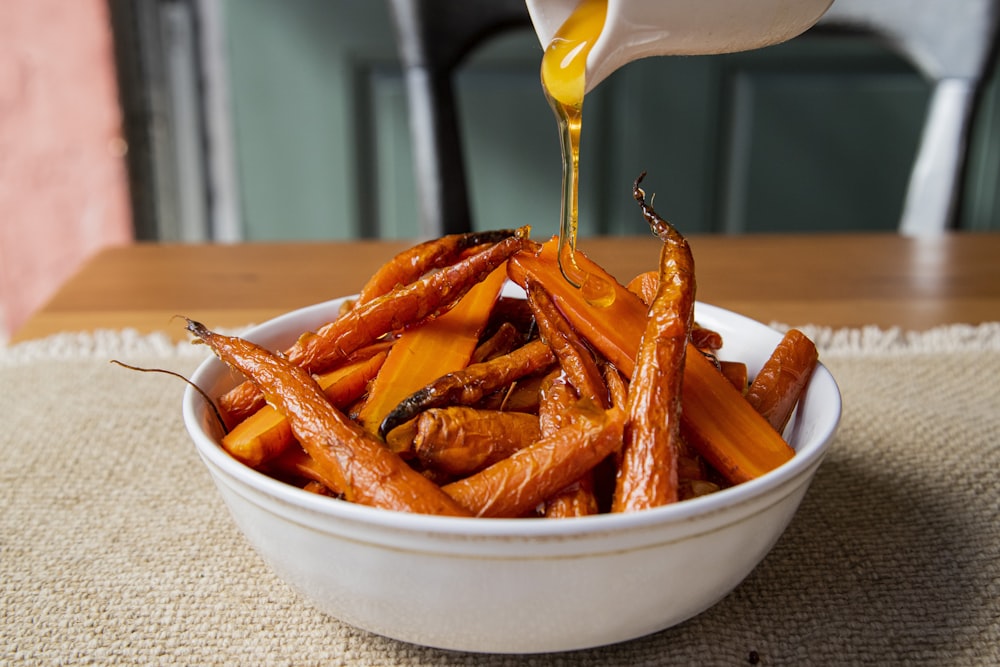 a white bowl filled with carrots sitting on top of a table