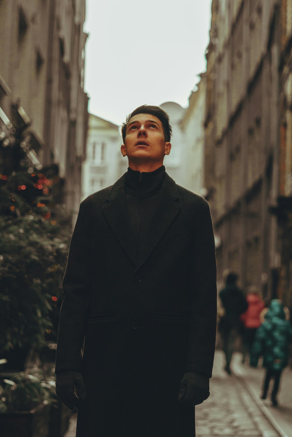 a man in a black coat standing on a street