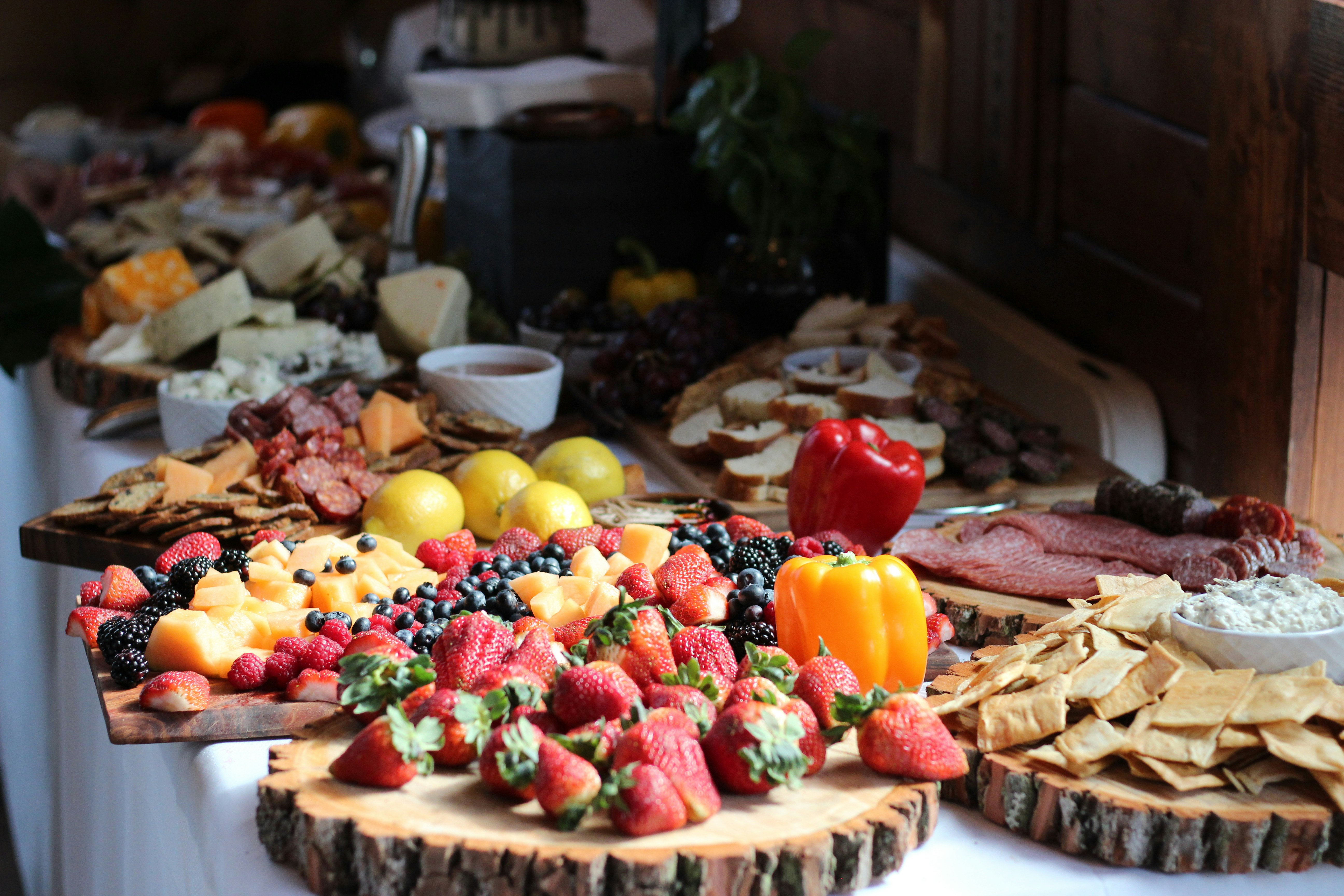 Gourmet food platter with artisan cheeses, crackers, and fruits on wooden board