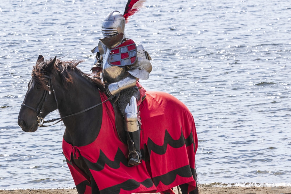 Un uomo vestito con un'armatura che cavalca un cavallo sulla spiaggia