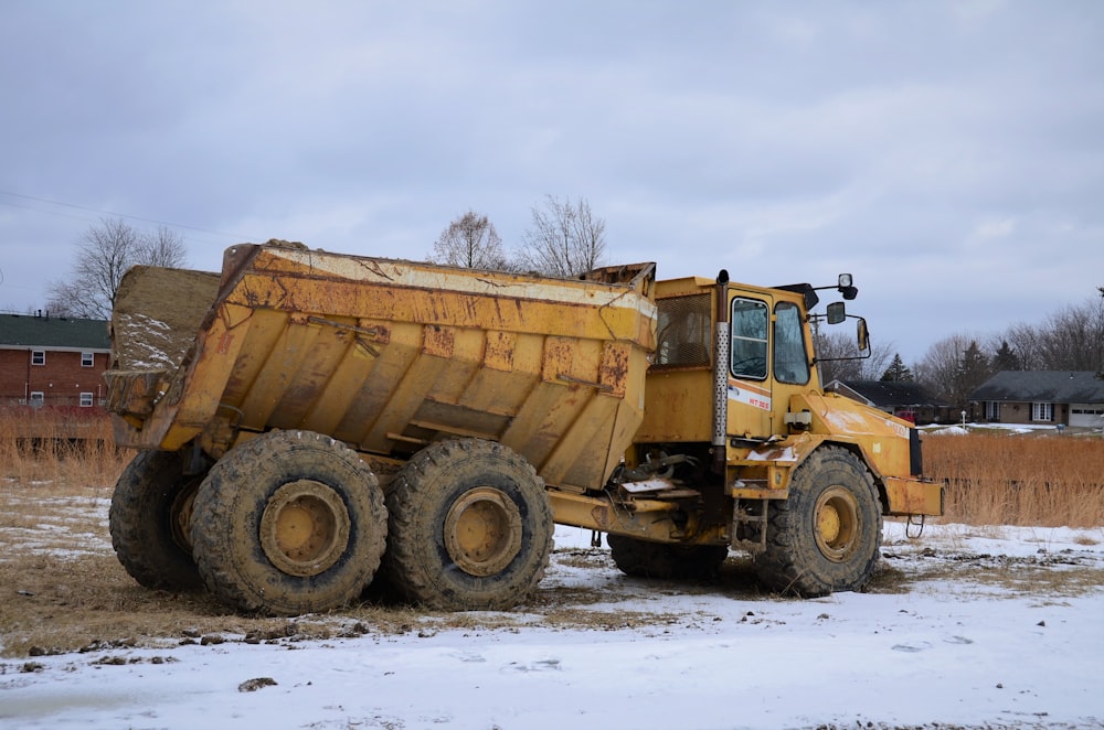 a large yellow dump truck parked on a snow covered field