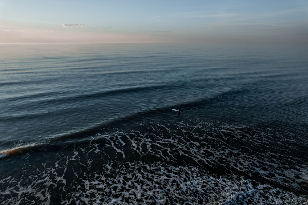 a person standing on a surfboard in the middle of the ocean