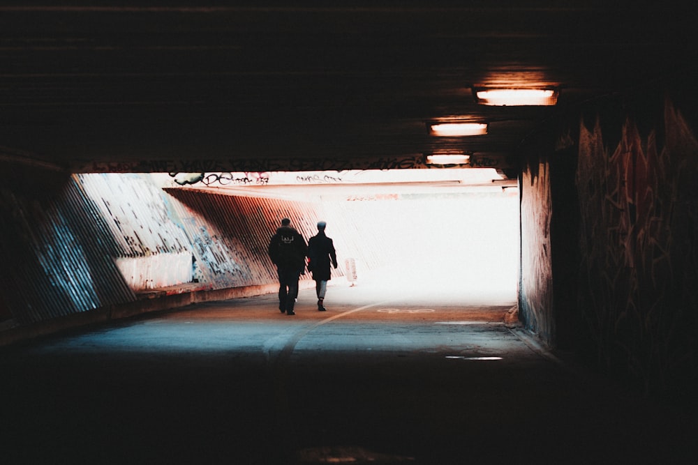 a couple of people that are walking in a tunnel