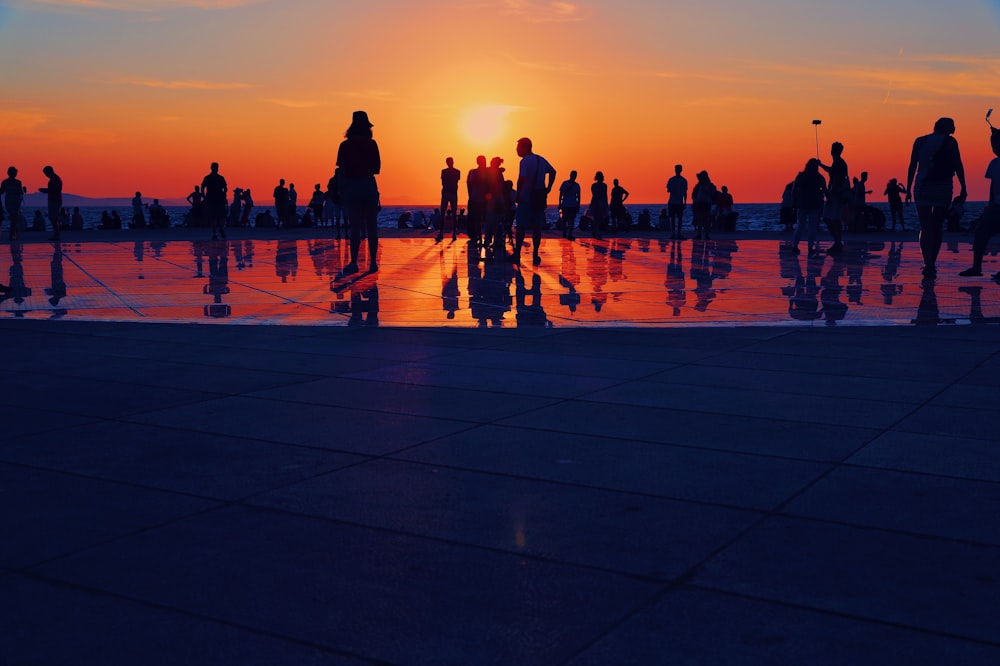 a group of people standing around a pool at sunset