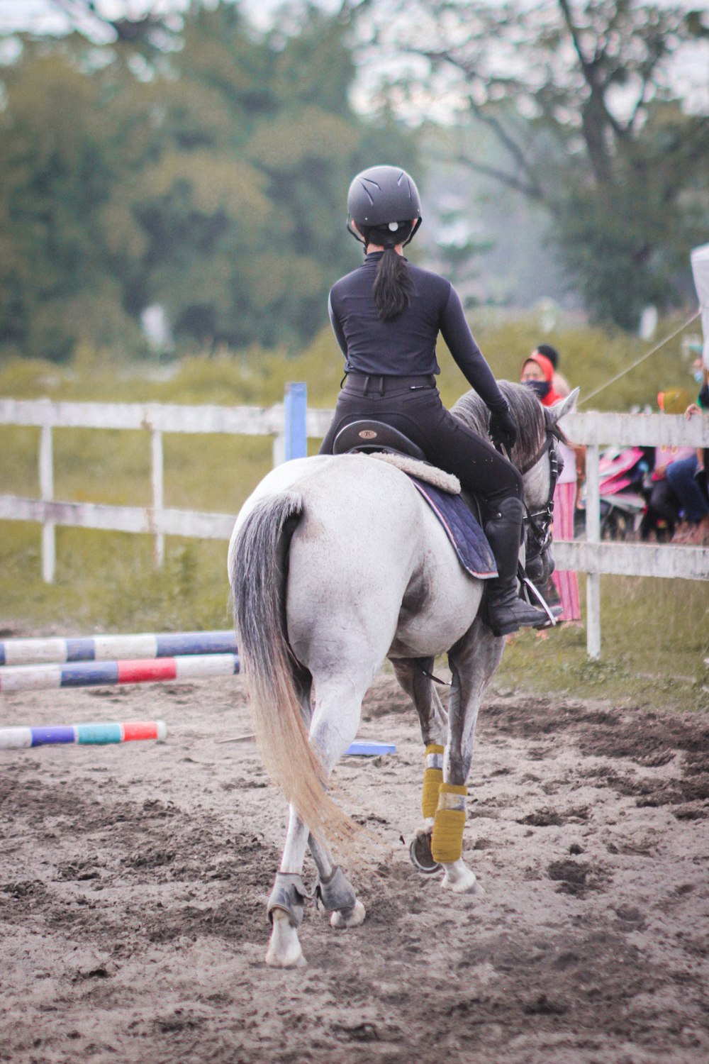 a woman riding on the back of a white horse