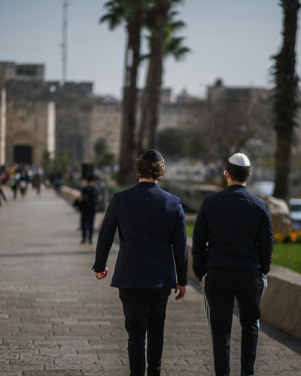 two men in suits walking down a sidewalk