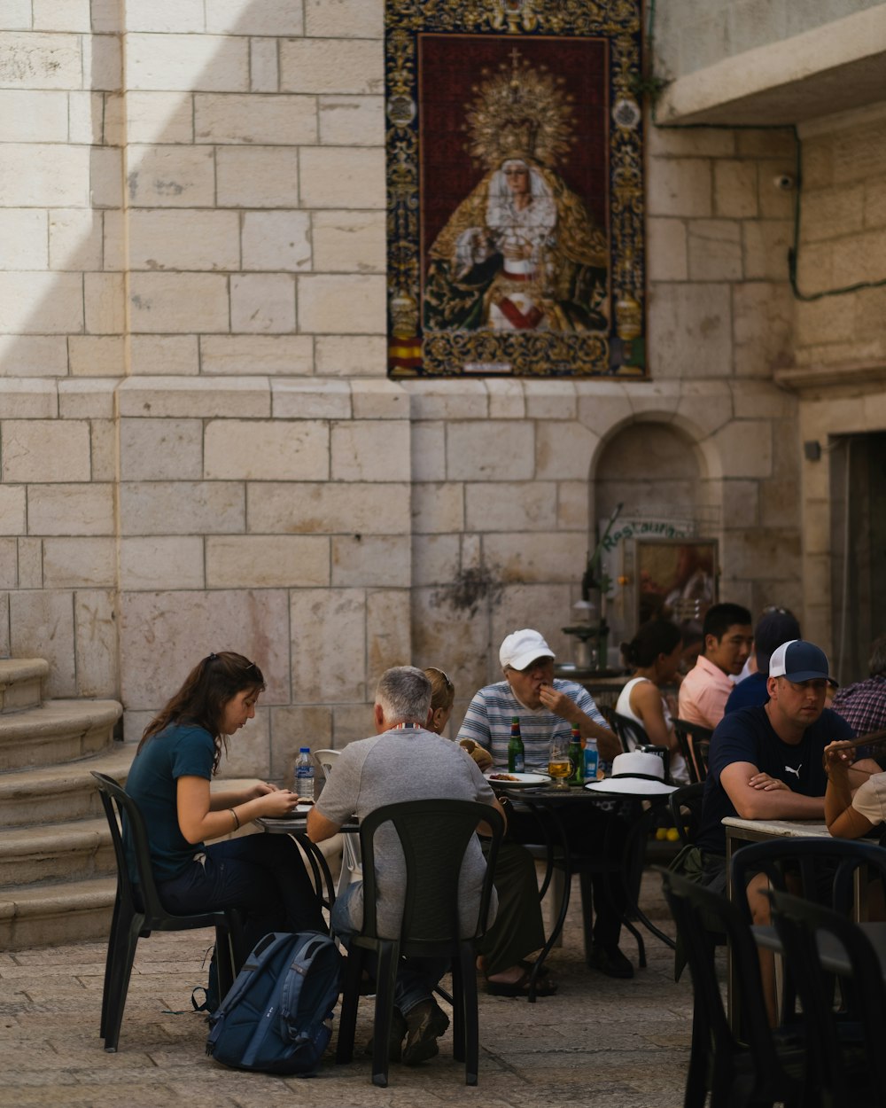 a group of people sitting at tables in a courtyard