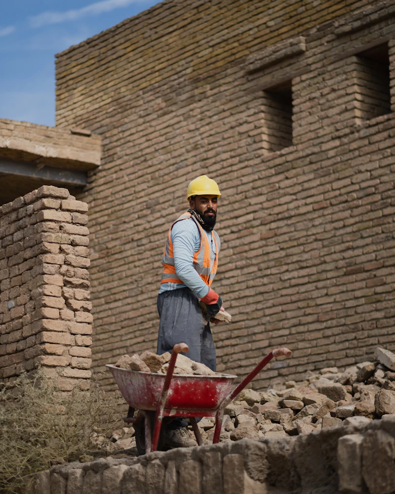 Construction worker on site with a wheelbarrow, representing the hands-on craftsmanship behind our work