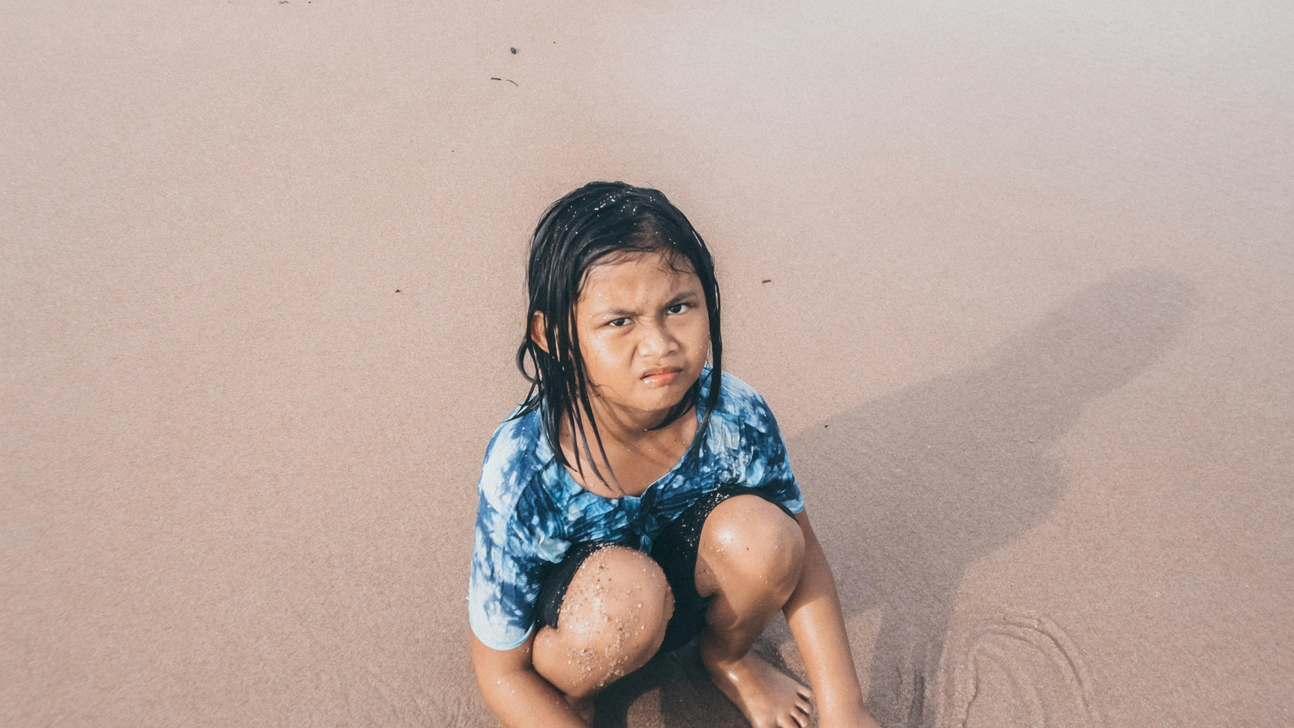 A young girl looks upset at the beach.