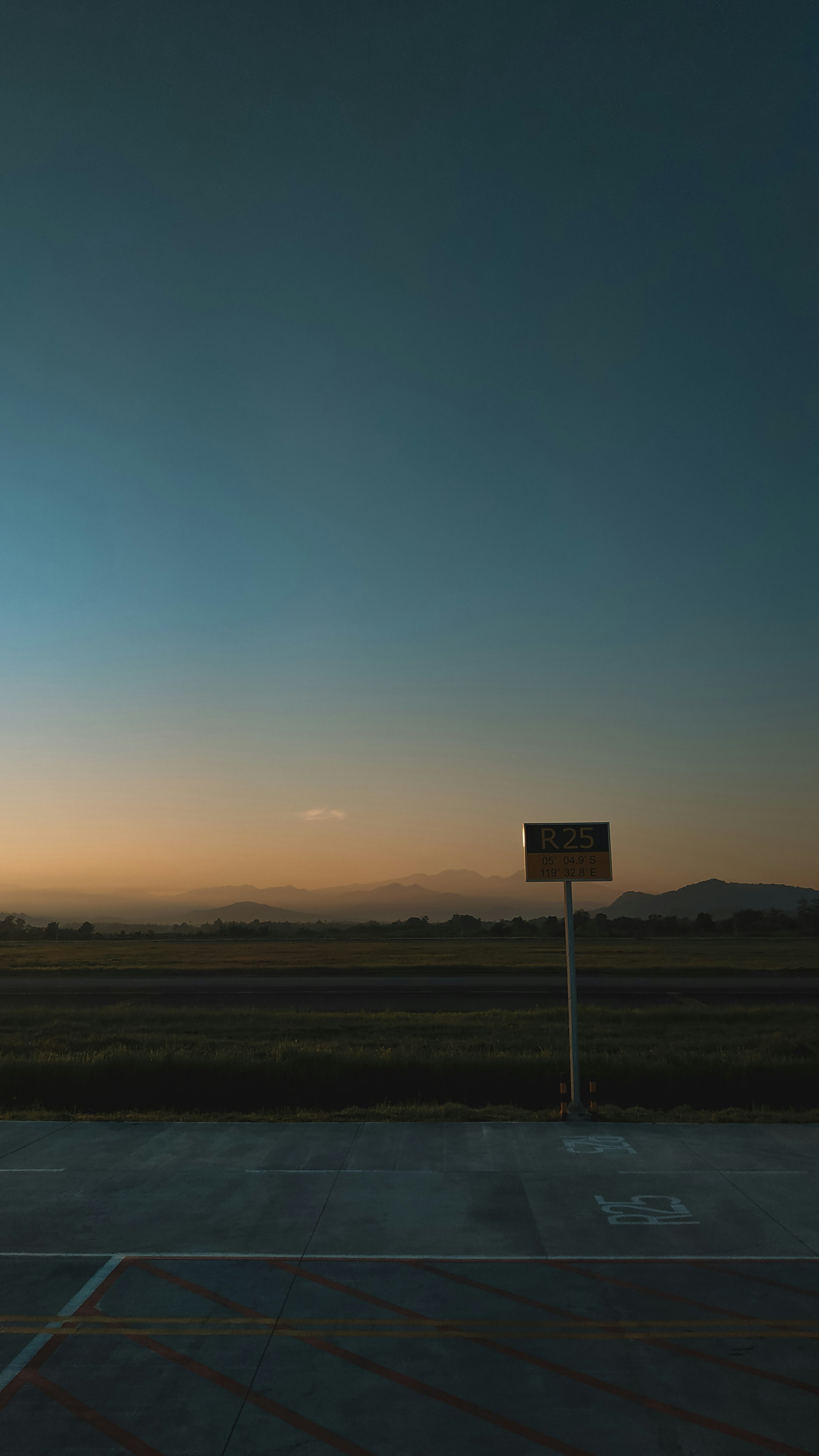 Sunset scene with a sign and vast fields.