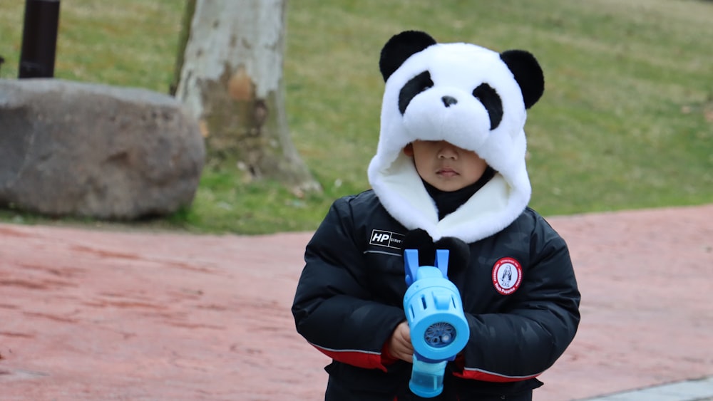 a little boy wearing a panda hat and holding a pair of scissors