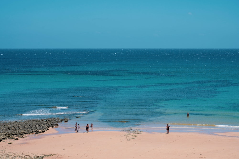 a group of people standing on top of a sandy beach