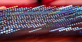 A colorful and blurred image depicts the letters of a keyboard. The keys are distorted and stretch across the image, creating a dynamic and futuristic visual effect. The bright, multicolored lights reflect off the surface, with hues of red, blue, green, and yellow dominating the scene.