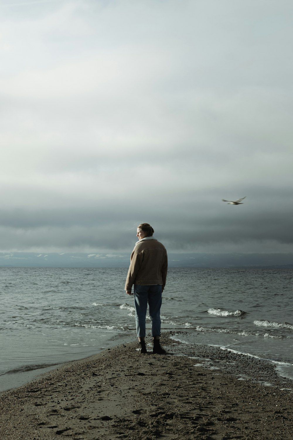 a man standing on top of a beach next to the ocean