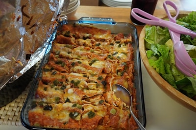 Close-up of a colorful plate with 15 freshly made enchiladas potosinas topped with crema, cheese, and avocado slices.