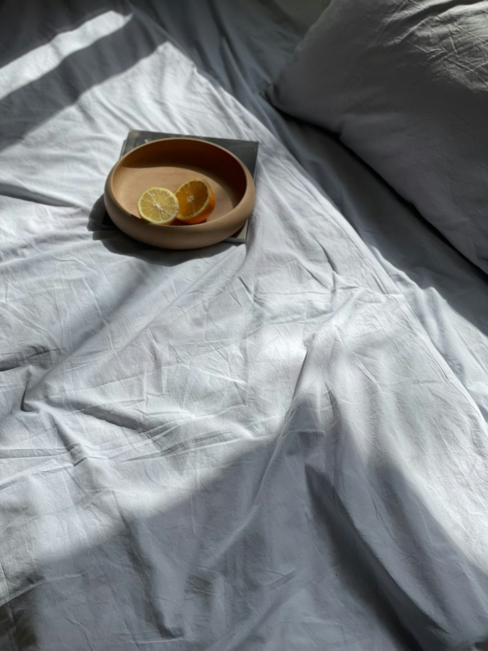 a bowl of lemons on a bed with white sheets