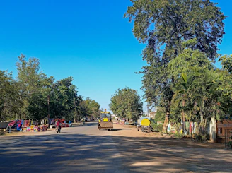 A freshly paved highway stretching through a green Cameroonian landscape with construction workers and heavy machinery.
