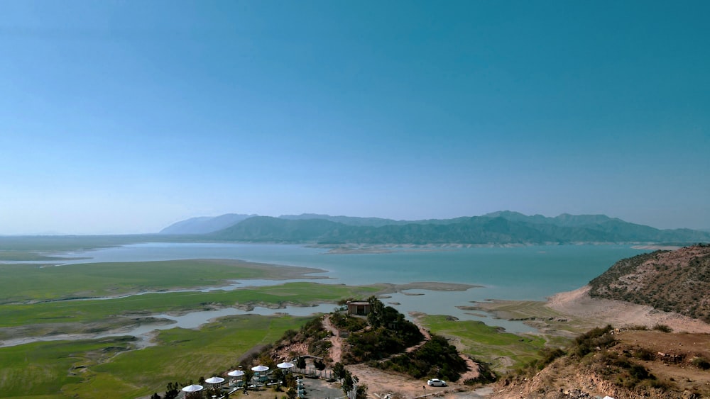 a large body of water sitting next to a lush green field