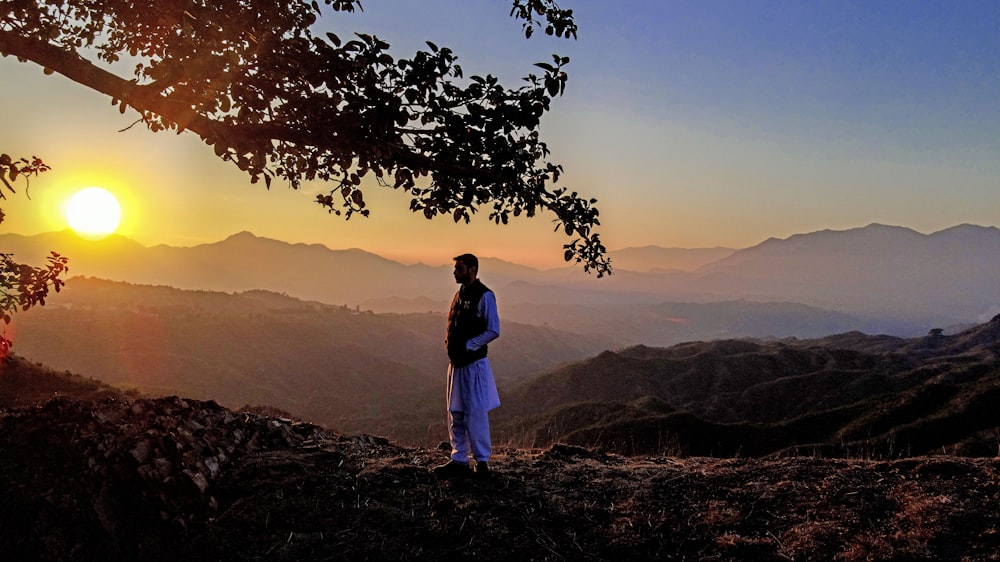 a man standing on top of a lush green hillside