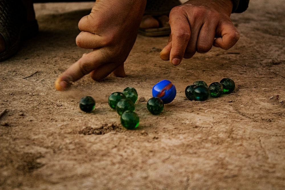 a man is playing with marbles on the ground