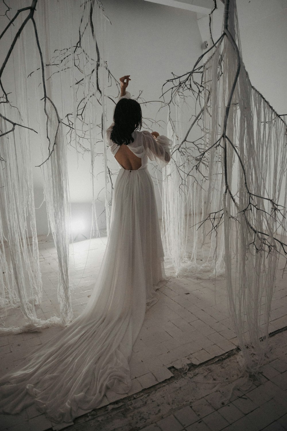 a woman in a white dress standing in front of a tree