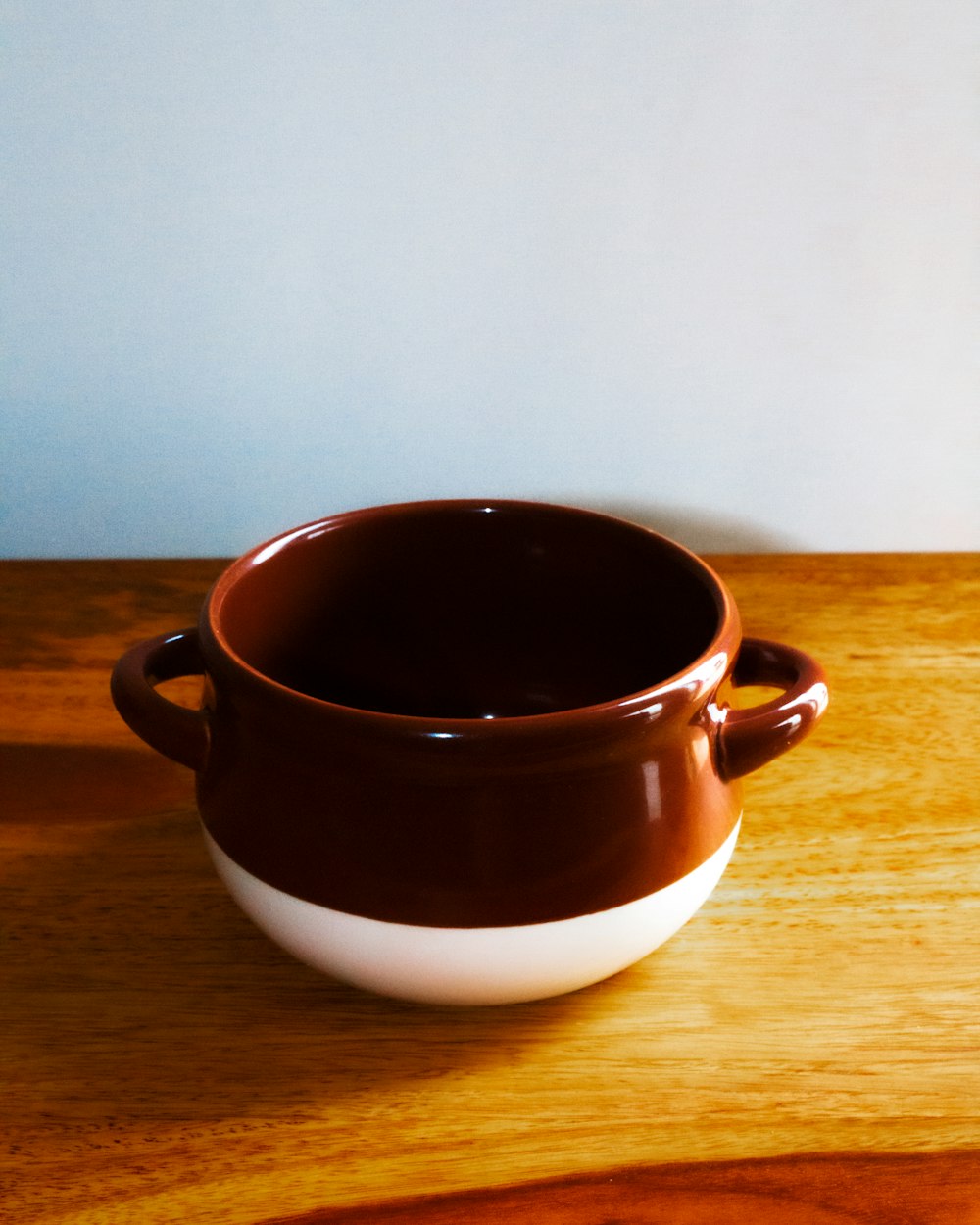 a brown and white bowl sitting on top of a wooden table