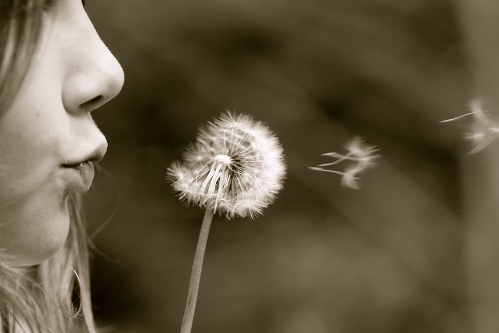 a young girl blowing on a dandelion