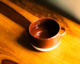 Close-up of a ceramic mug with warm earthy glaze on a wooden table.