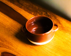 A warm, colorful ceramic mug resting on a wooden table with soft natural light.