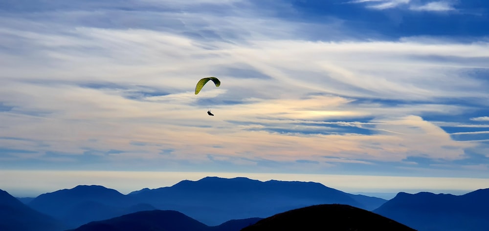 a paraglider is flying over a mountain range