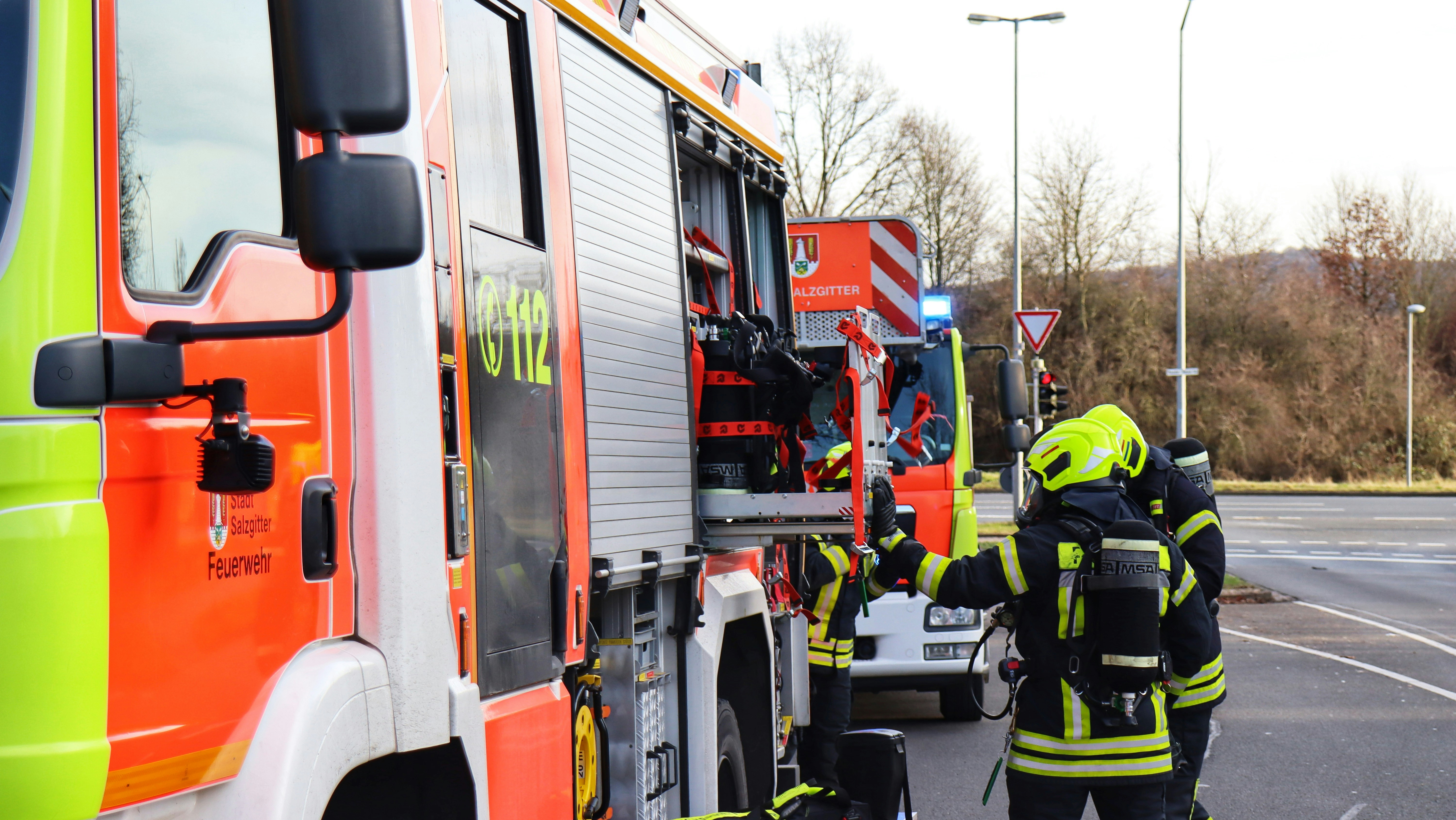 a couple of fire fighters standing next to a fire truck