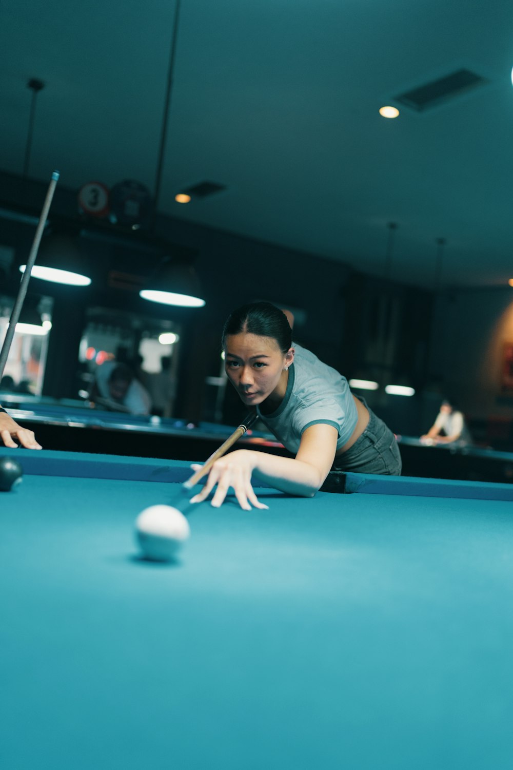 a woman leaning over a pool table to hit a ball