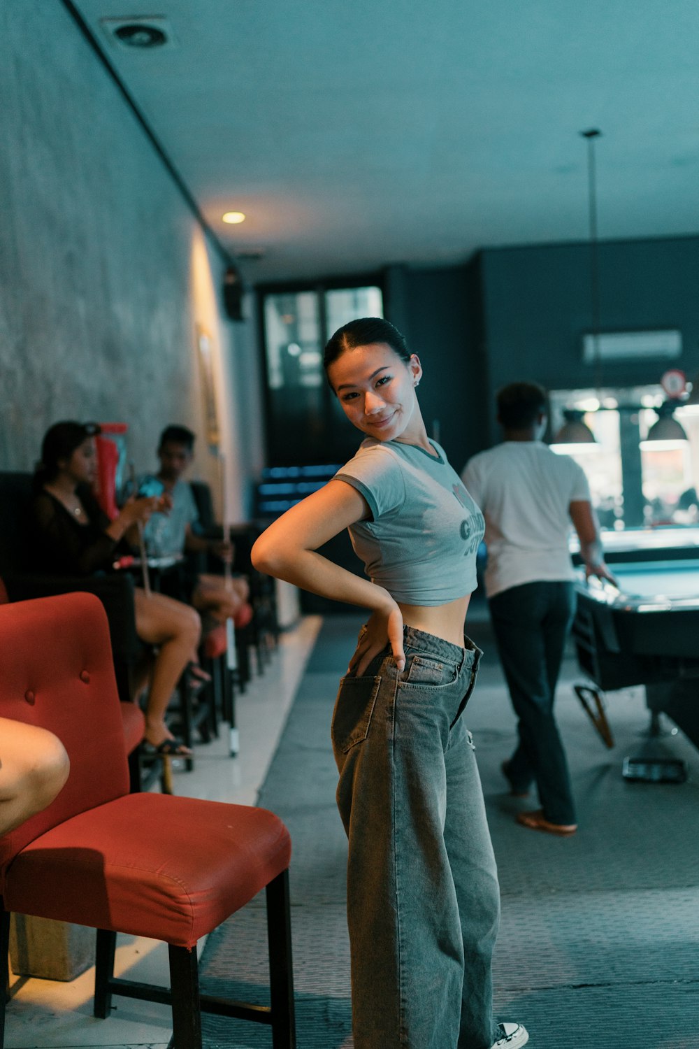 Une femme debout devant une table de billard