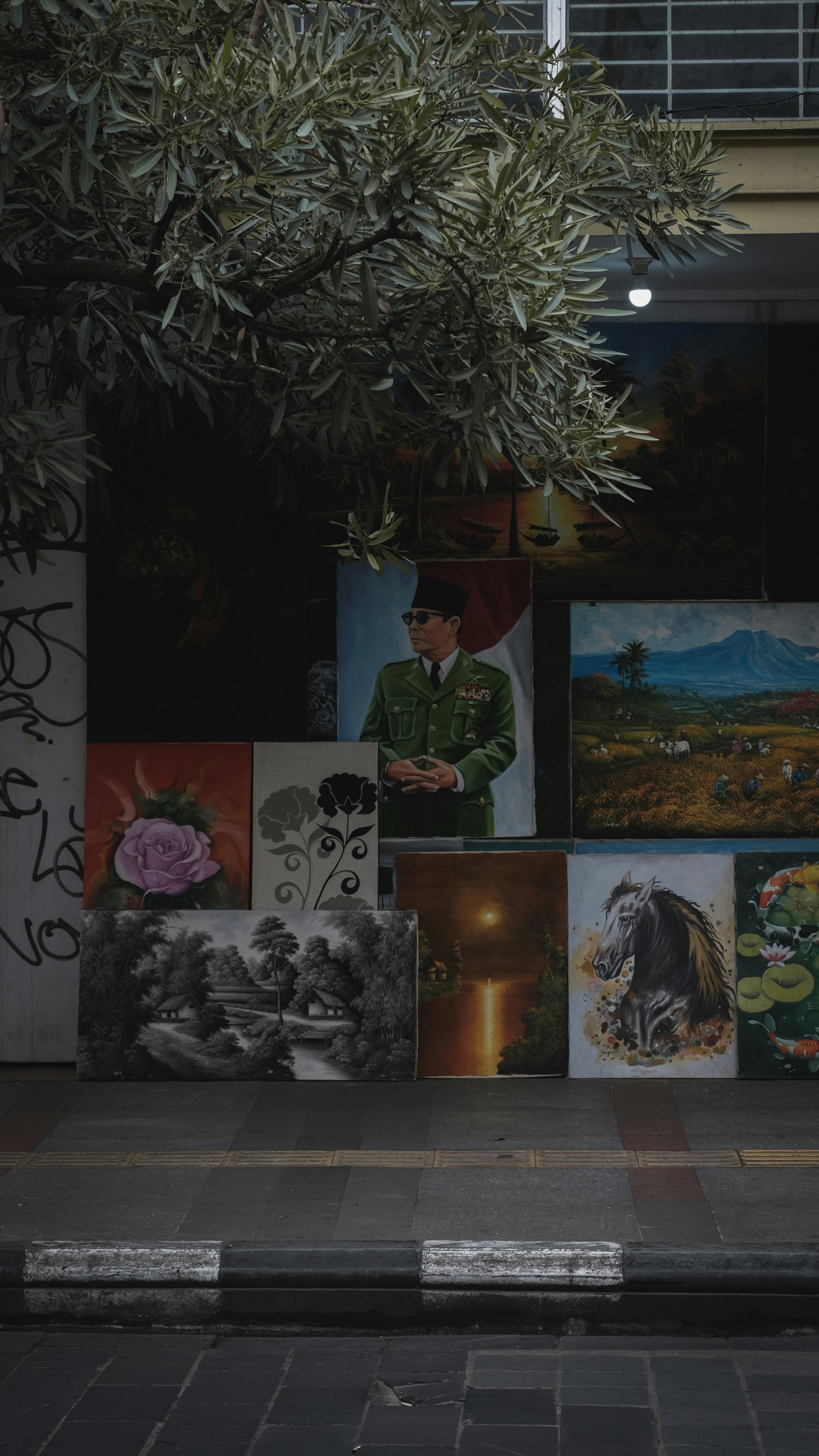 a man walking down a street past a wall covered in pictures