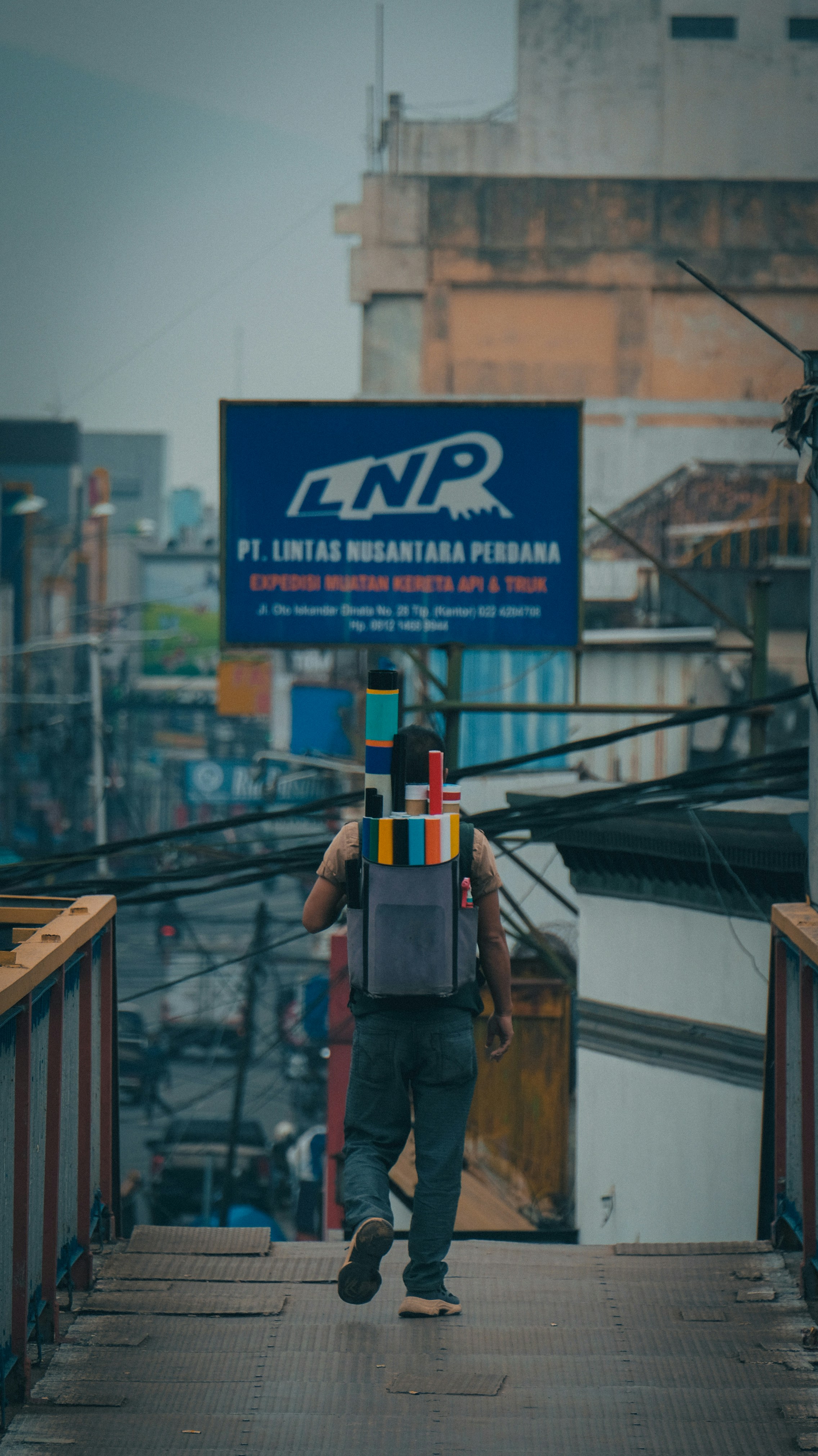 a man walking across a bridge carrying a backpack