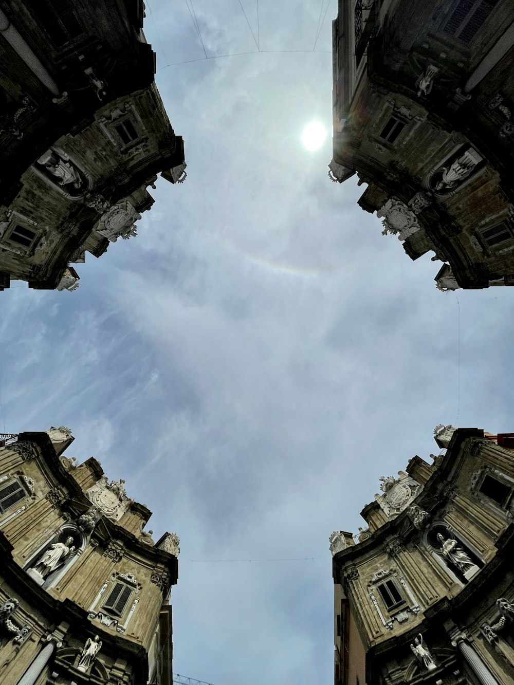 looking up at a tall building with a rainbow in the sky