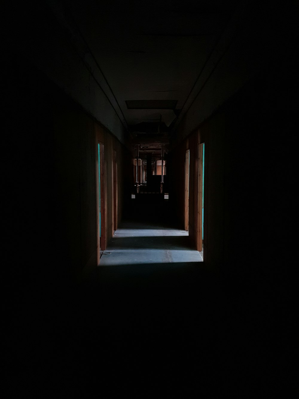 a dark hallway with a light at the end of it