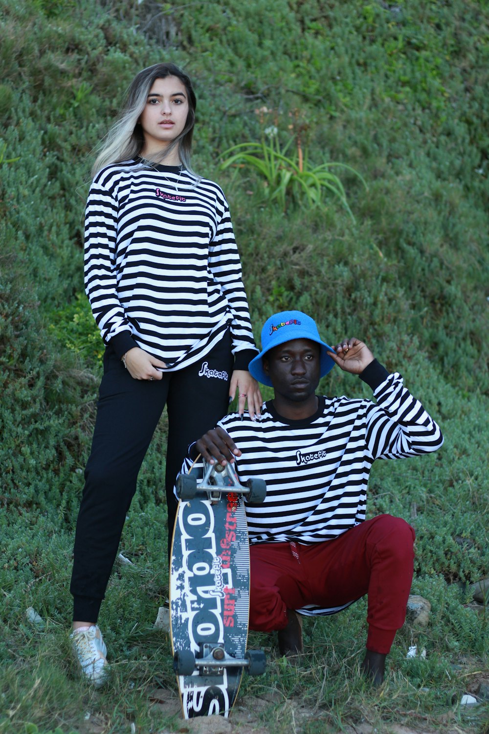a man and a woman posing with a skateboard