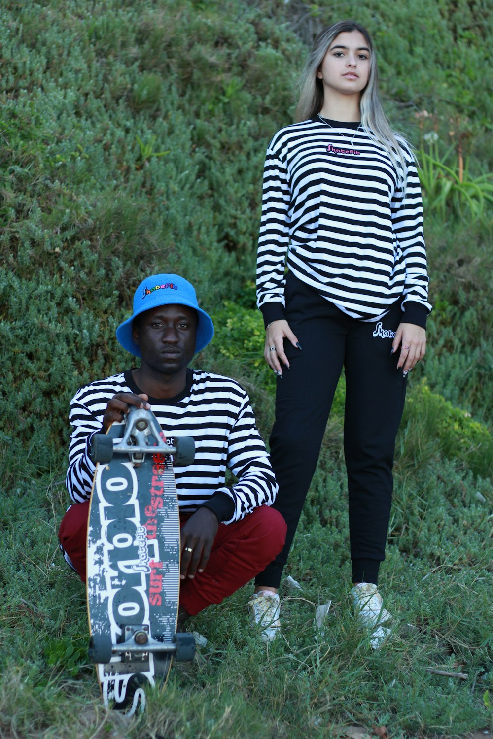 a woman standing next to a man holding a skateboard